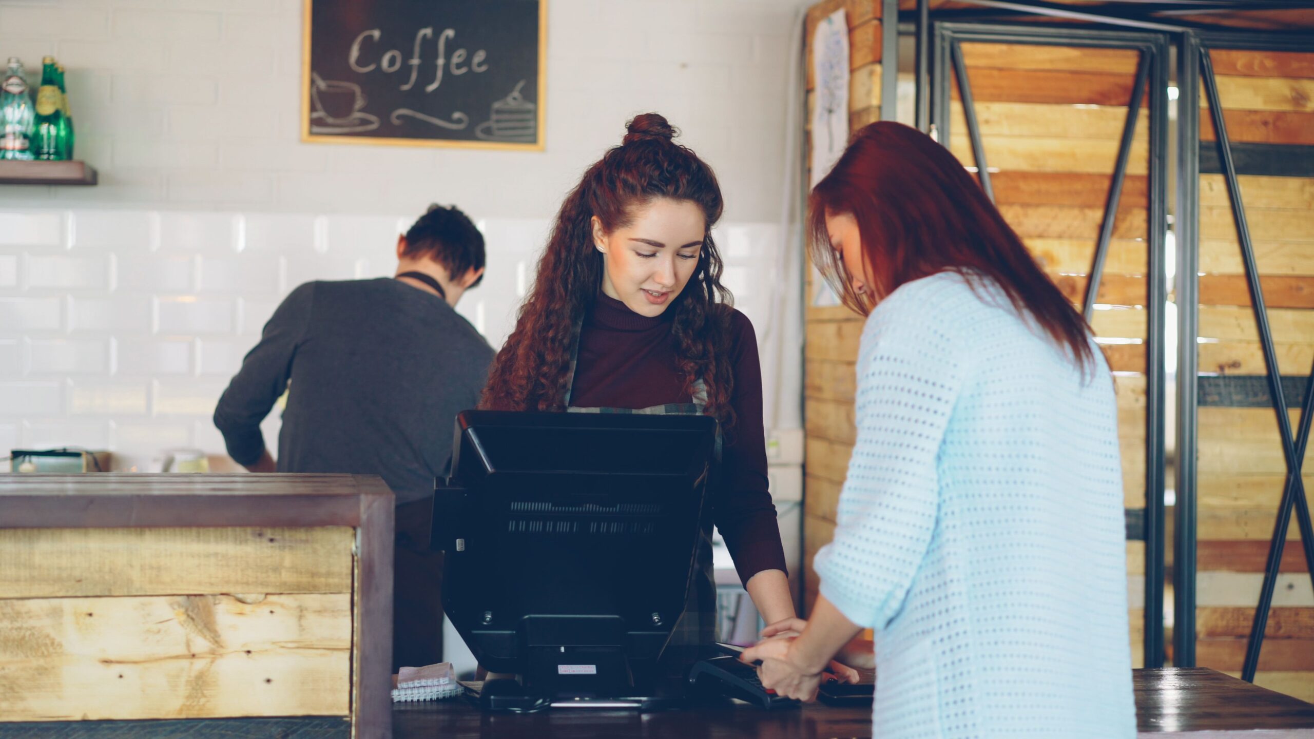 Barista assists customer at cozy coffee shop counter.